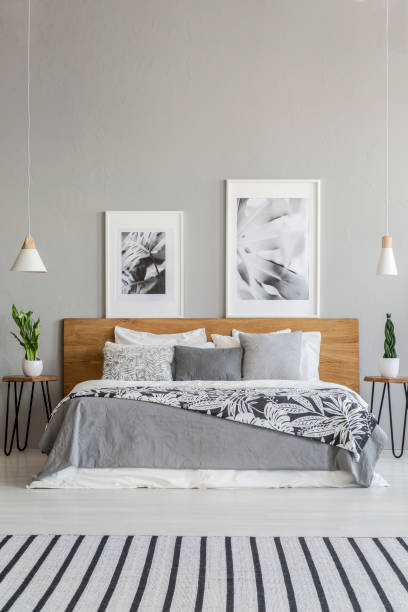 posters on wooden headboard of bed with patterned blanket in grey bedroom interior with carpet. real photo - headboard imagens e fotografias de stock