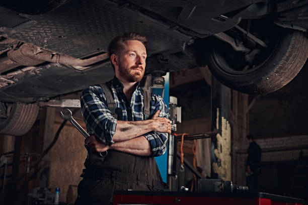 istock Mechanic crossed hands while standing under lifting car in a repair garage. 1019976660