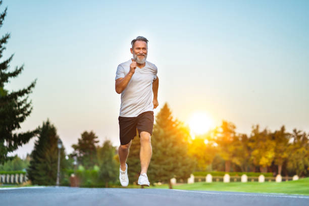 The elderly man running on the road on the sunrise background