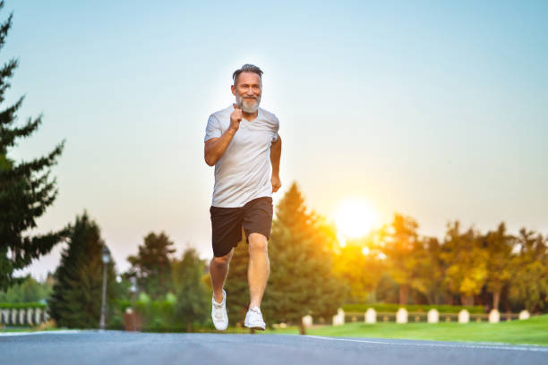 The elderly man running on the road on the sunrise background stock photo