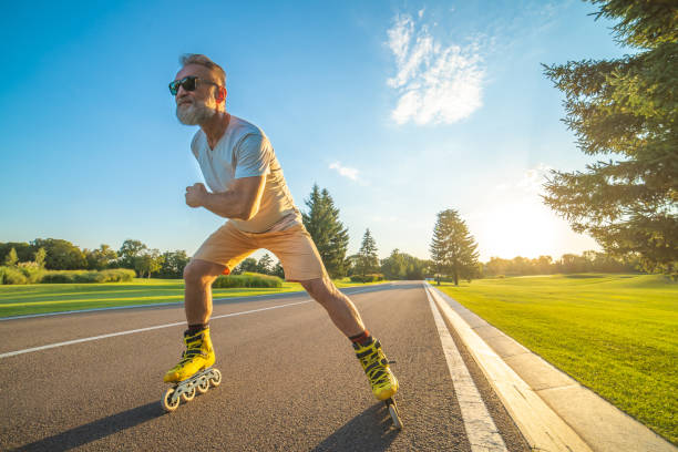 The elderly man in sunglasses rollerblading on the road on the sunset background The elderly man in sunglasses rollerblading on the road on the sunset background inline skating stock pictures, royalty-free photos & images