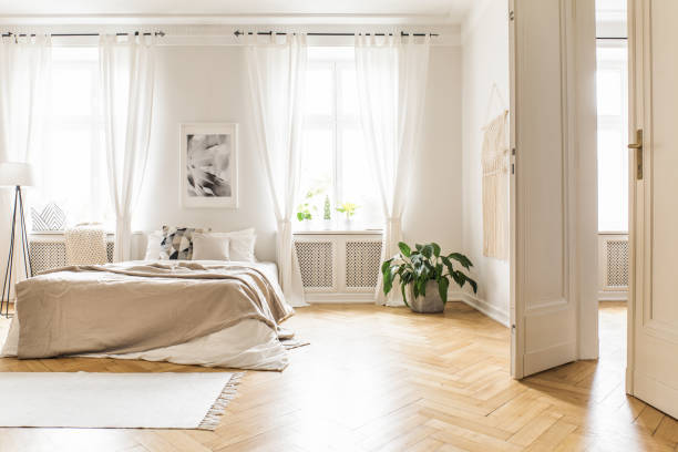 Spacious and bright bedroom interior with beige decorations, hardwood floor and a book on the window sill seat Spacious and bright bedroom interior with beige decorations, hardwood floor and a book on the window sill seat herringbone stock pictures, royalty-free photos & images