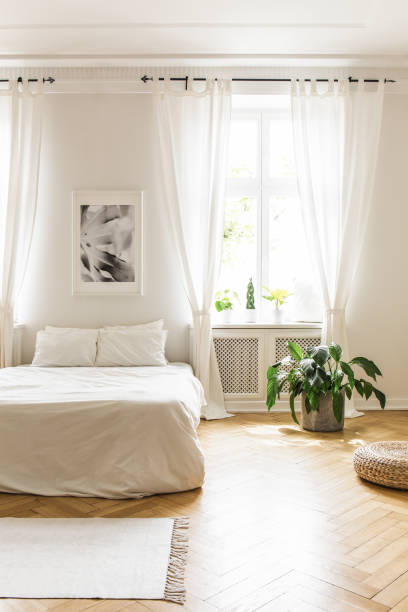 istock Minimalist, white hotel bedroom interior with a comfy double bed, herringbone hardwood floor and natural light coming through the big windows 1020001654