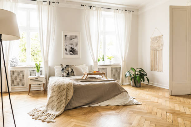 istock Framed poster on a white wall above a cozy double bed with beige sheets and breakfast tray in a spacious, sunny bedroom interior 1020001672