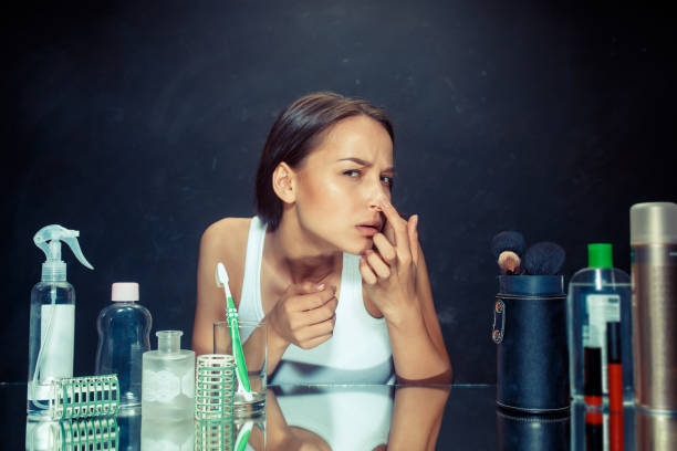 istock Unsatisfied young woman looking at her self in mirror on black background 1020004714