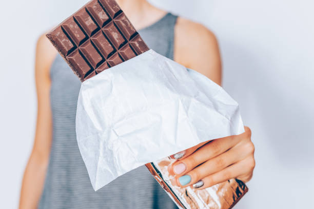 istock Woman's hand holding unwrapped dark chocolate bar 1020006026
