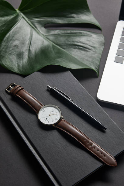istock Notebook with pen and watch by laptop on black background 1020014640