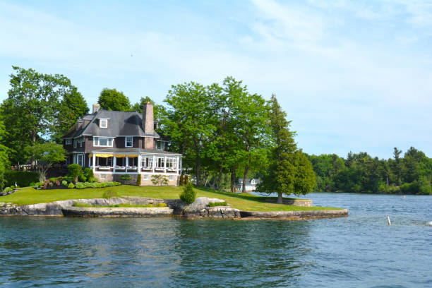 Island with house, cottage or villa in Thousand Islands Region St Lawrence River's Thousand Islands, Canada and United States of America- June 19, 2016- Island with house, cottage or villa in Thousand Islands Region in sunny summer day in Kingston, Ontario, Canada. 1000 Islands near Gananoque, ON. Canadian vacation kingston harbour stock pictures, royalty-free photos & images