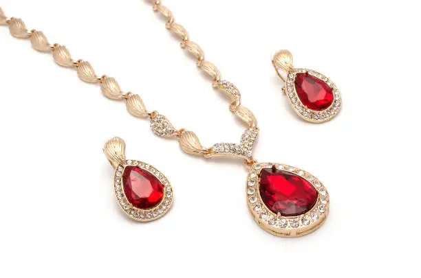 Photo of gold necklace and earrings with rubies isolated on white