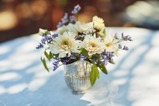 Shot of a metal vase filled with flowers on table at a tea party outside