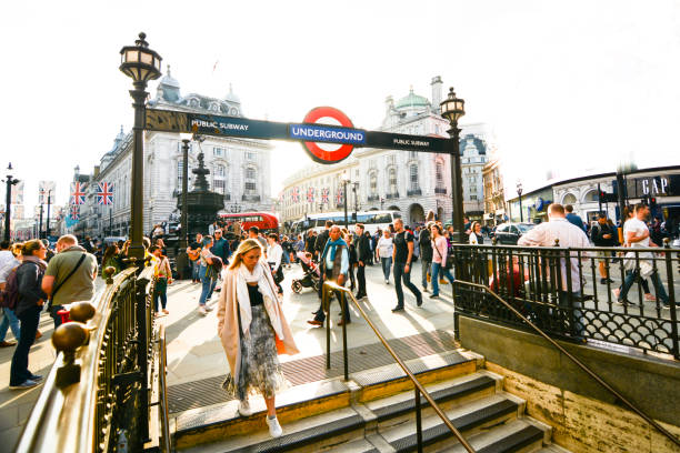 Busy crowds of people at Piccadilly Circus at the steps of the underground tube station, a famous landmark and busy tourist destination
