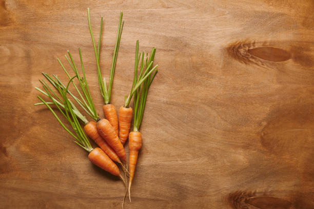 istock Bunch of raw carrots on wooden table 1020038186