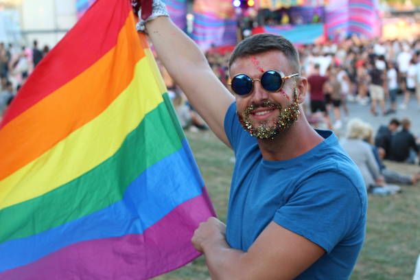 miembro lgbti disfrutando de un desfile - homosexual rainbow gay pride flag flag fotografías e imágenes de stock