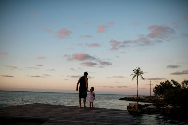 istock Silhouette of father and daughter on a dock at sunset 1020049018