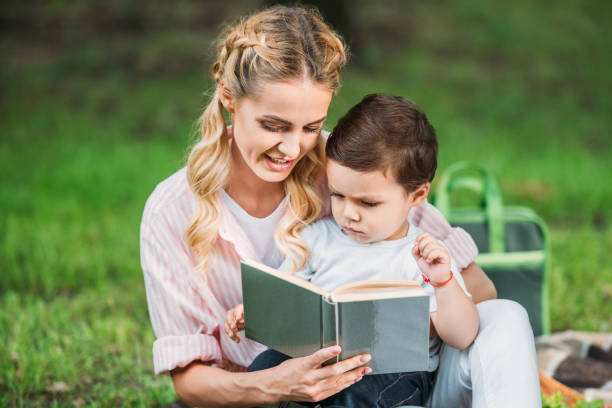 istock happy mother with son reading book at park 1020057602