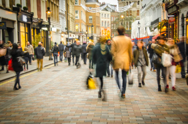 High Street shopping street A busy high street scene with a couple holding hands and walking past fashion shops retail place stock pictures, royalty-free photos & images