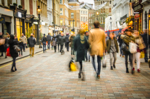 High Street shopping street A busy high street scene with a couple holding hands and walking past fashion shops retail high street stock pictures, royalty-free photos & images