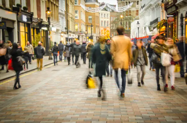 A busy high street scene with a couple holding hands and walking past fashion shops