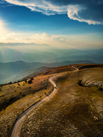 Mountain road with car at sunset