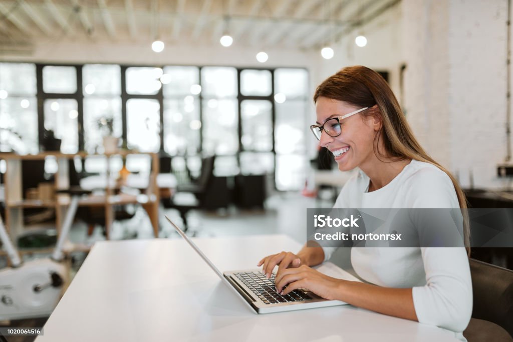 Superbe jeune femme à l’aide d’ordinateur portable au bureau lumineux. Gros plan. - Photo de Cotravail libre de droits