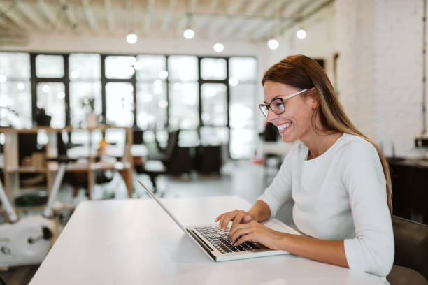 superbe jeune femme à l’aide d’ordinateur portable au bureau lumineux. gros plan. - coworking photos et images de collection