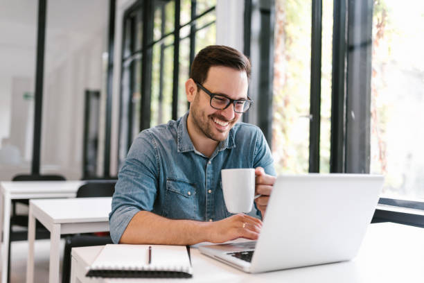 istock Handsome freelancer using laptop and drinking coffee in bright modern enviroment. 1020064604