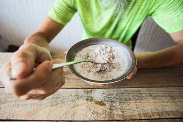 Unrecognizable man eating oatmeal with chia seed and yogurt, having breakfast at home