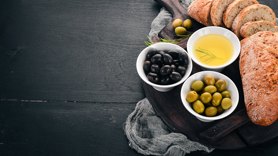 Olives and bread. Italian cuisine. On a wooden table. Top view. Free space for text.