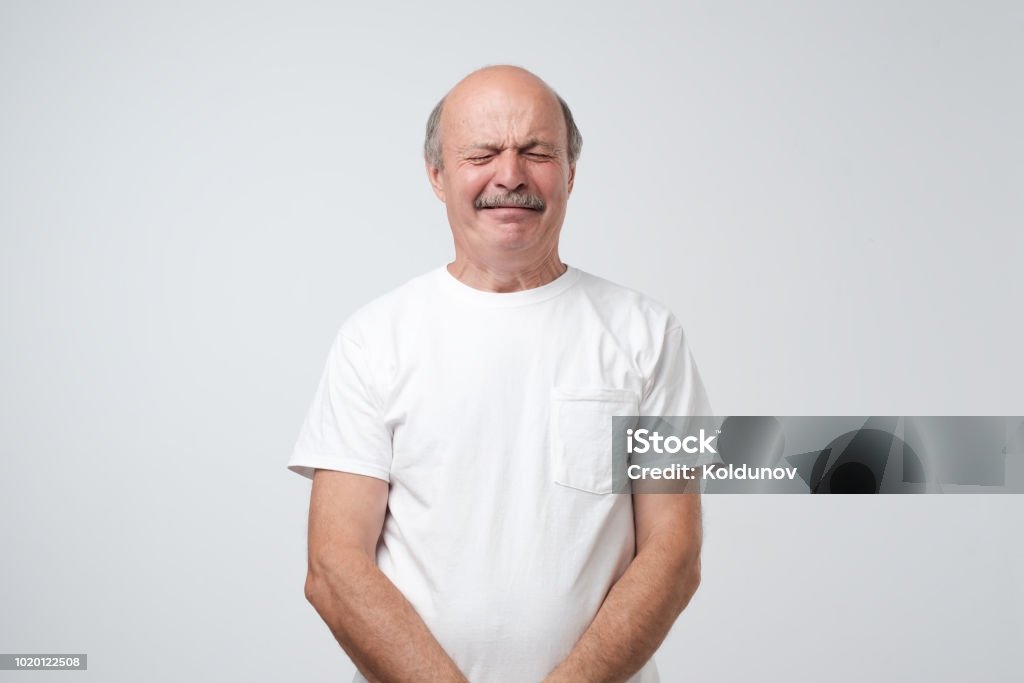 Malheureux homme senior comme weeper pleurer debout sur fond gris. Il est choqué et bouleversé. - Photo de Grimace de crispation libre de droits