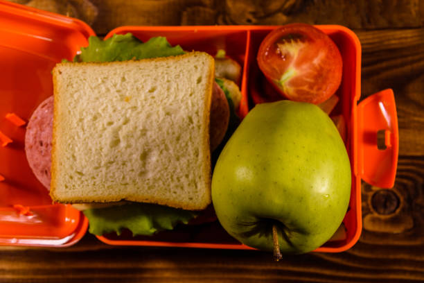 istock Lunch box with sandwich, cucumbers, green apple and tomatoes on wooden table. Top view 1020157778