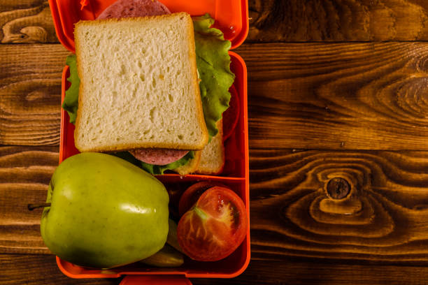 istock Lunch box with sandwich, cucumbers, green apple and tomatoes on wooden table. Top view 1020157786
