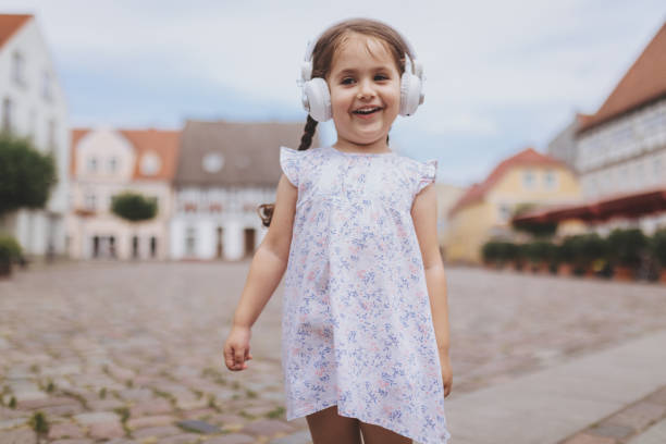 sourire d’enfant, écouter de la musique sur le casque lorsque vous vous trouvez sur une ville carrée - north sea audio photos et images de collection