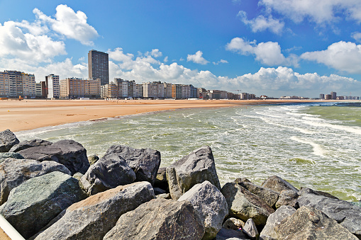 View from the sandy beach on the city. Summer day in Ostende, Belgium. A view of city buildings under construction from the desert beach