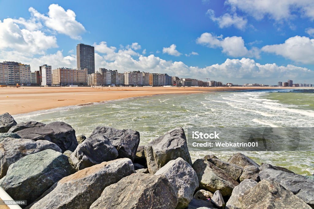 View from the sandy beach on the city. Summer day in Ostende, Belgium View from the sandy beach on the city. Summer day in Ostende, Belgium. A view of city buildings under construction from the desert beach Ostend Stock Photo
