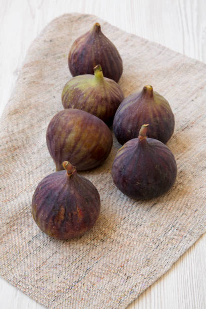 istock Fresh figs on cloth over white wooden surface, side view. 1020181716