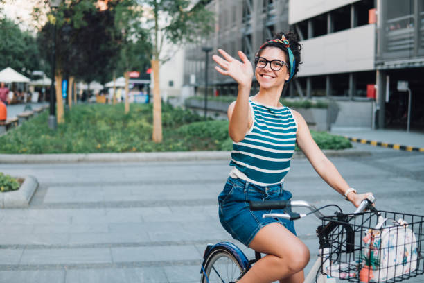 Woman smiling and waving her hand while riding bicycle