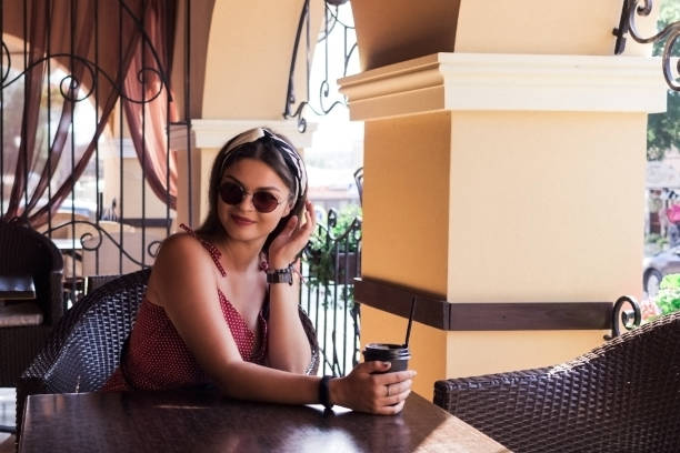 istock A girl in sunglasses drinks coffee at a table 1020229930