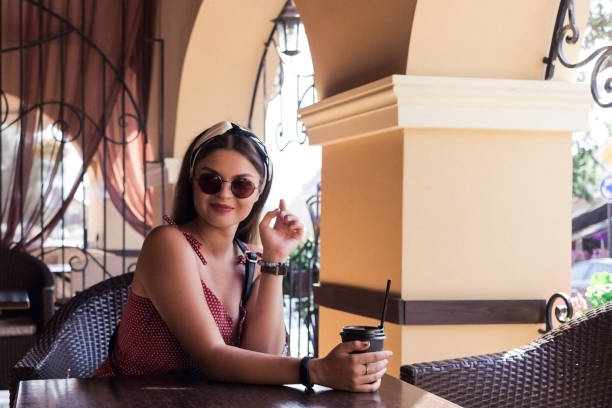 istock A girl in sunglasses drinks coffee at a table 1020229960