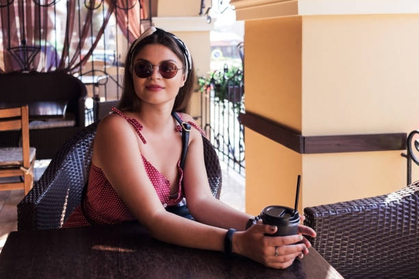 istock A girl in sunglasses drinks coffee at a table 1020229970