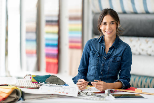 Interior designer working at her workshop choosing fabrics Portrait of a happy interior designer working at her workshop choosing fabrics and looking at the camera smiling. **DESIGN ON DOCUMENTS WERE MADE FROM SCRATCH BY US** interior designer stock pictures, royalty-free photos & images