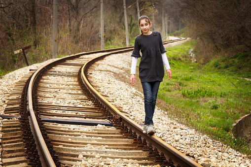 Young girl walking on rails and thinking