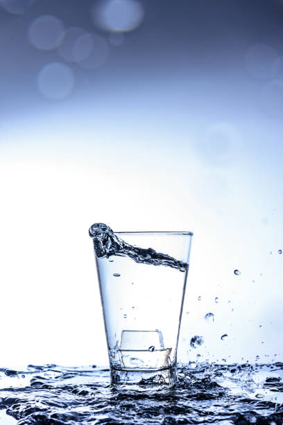 istock Ice dropping and water splashing in the glass with reflection on the mirror table and isolated on white background. 1020281630