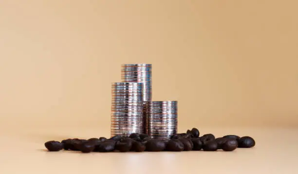 Photo of Three pile of coins and coffee beans.