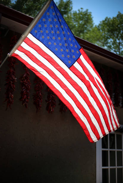 istock Santa Fe, NM: Sunlit US Flag Blowing; Ristras in Background 1020310142