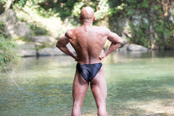 Japanese bald head bodybuilder posing the back lat spread at the river Japanese bald head bodybuilder posing the back lat spread at the river in summer lat spread bodybuilder stock pictures, royalty-free photos & images