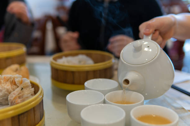 A close-up photograph of hot Chinese tea being poured into teacups at a dim sum restaurant
