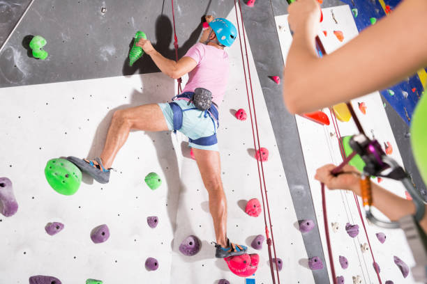 Female Climber in white shirt with serious face and her Son below starting his try on rock climbing wall