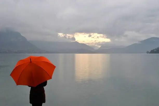 Photo of girl with umbrella meets sunrise on Lake Annecy in France