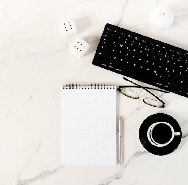 istock Top view of white marble office table with keyboard. glasses, notebook, cup of coffee and supplies. Top view with copy space. Flat lay. 1020367882