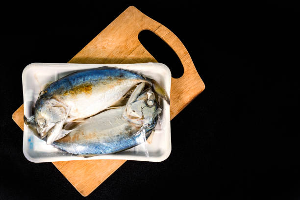 istock Two fish in packaging from supermarket on the wood plate. 1020383440
